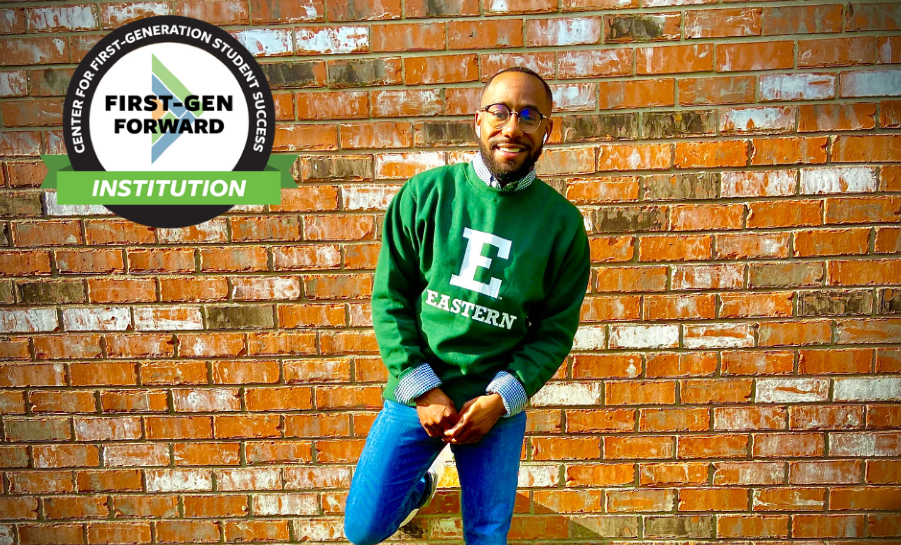 Student leaning against brick wall on campus