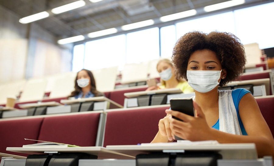 Black female in class with phone and mask
