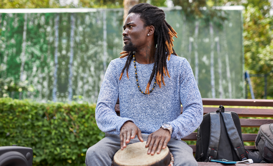 Black adult student sitting outside playing drum