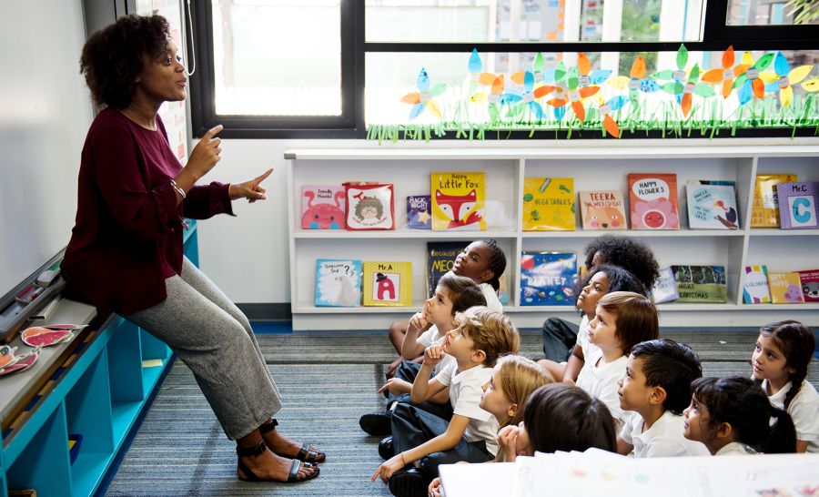 Black female K-12 teacher lectures elementary school students