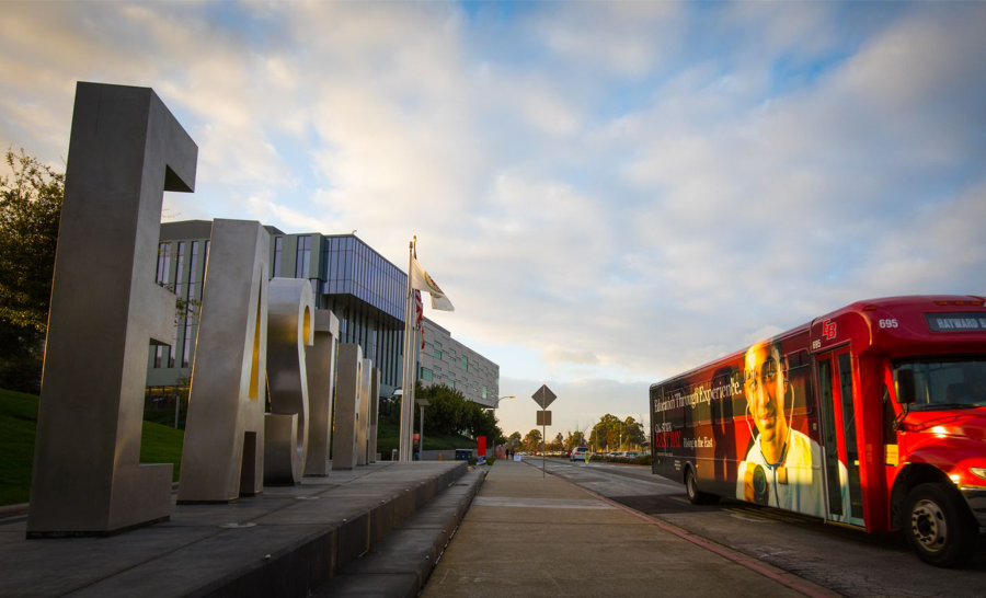 CSU East Bay Campus at sunrise with a red bus in the foreground
