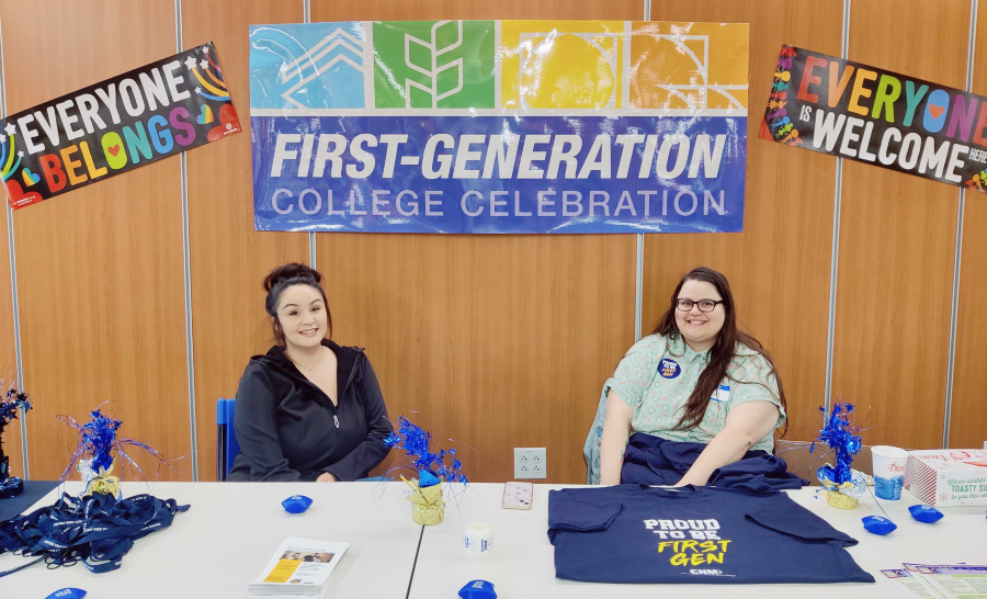 Two staff members tabling with first-gen swag in front of FGCC logo banner