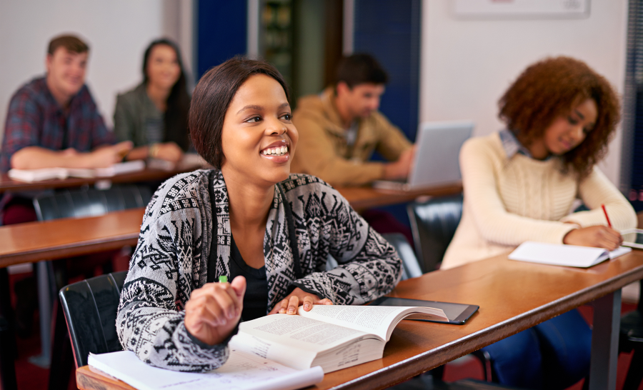 Black female student smiling seated at desk in classroom