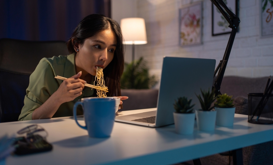 Female student eating in front of laptop
