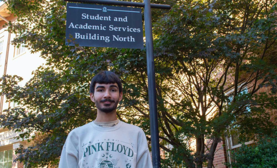 University of North Carolina at Chapel Hill Student poses below Student and Academic Services Building Sign Outside