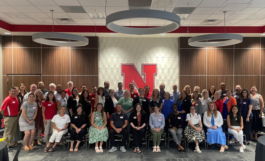 Faculty and Staff posing for a group photo in front of large, red N in UNL building