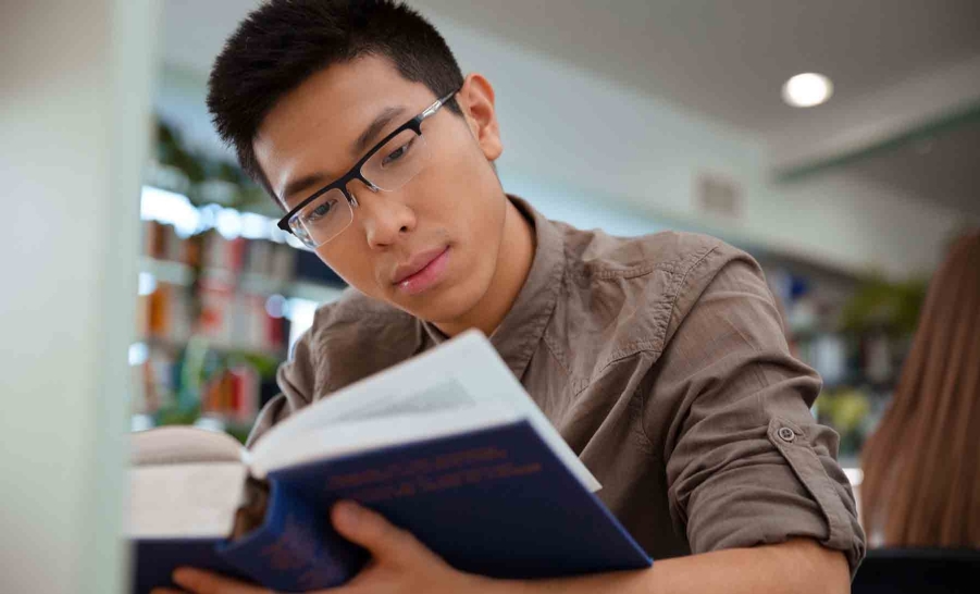 asian male reading in library
